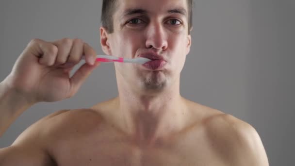 Молодой человек чистит зубы в ванной и перестает чувствовать зубную боль. — стоковое видео