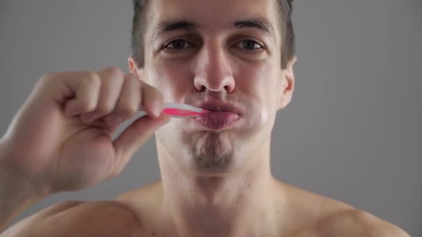 Junger Mann putzt sich im Badezimmer die Zähne und hört wegen Zahnschmerzen auf — Stockvideo