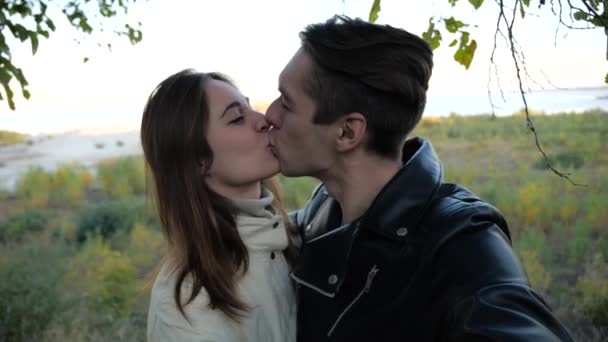Молодая семья делает селфи в поле и целуется — стоковое видео
