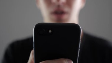 Genç adam akıllı telefon, Internet tarama ya da sosyal ağlar denetimi kullanarak closeup