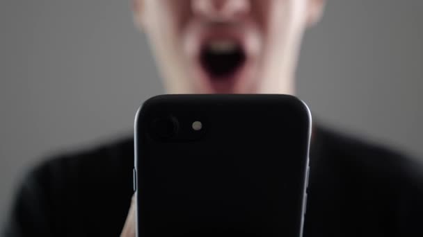 Close-up van Happy Young Man via Smartphone, browsen in Internet of sociale netwerken controleren op witte achtergrond — Stockvideo