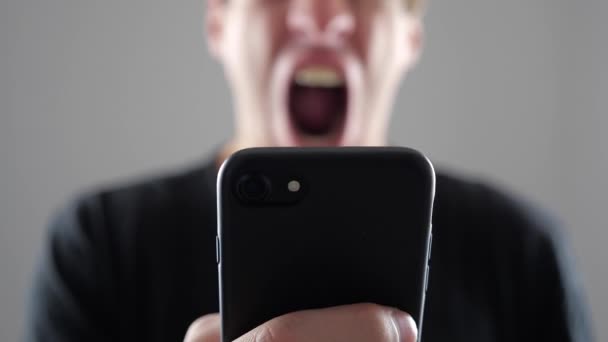 El hombre está enojado con el mensaje que leyó en el teléfono inteligente. Hombre enojado utiliza teléfono inteligente . — Vídeos de Stock