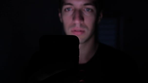 Genç adam akıllı telefon Internet tarama ya da sosyal ağlar denetimi geceleri kullanarak closeup — Stok video