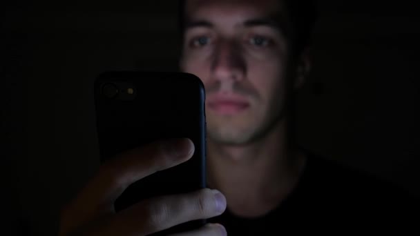 Крупним планом молода людина використовує смартфон вночі, перегляд в Інтернеті або перевірка соціальних мереж — стокове відео