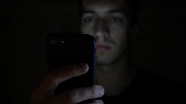 Крупный план молодого человека с помощью смартфона ночью, просмотр в Интернете или проверка социальных сетей — стоковое видео