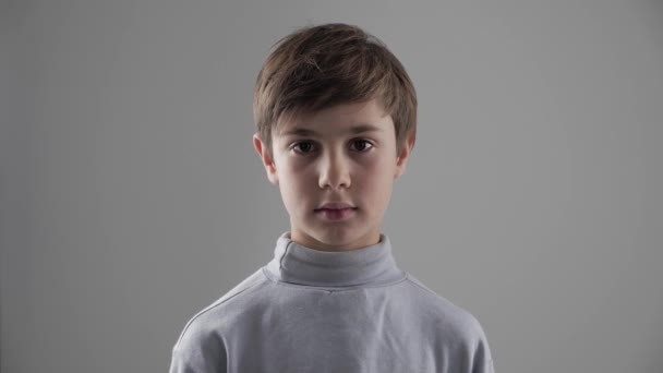 귀여운 젊은 11-12 년 오래 된 소년 보면 카메라 흰색 배경에 초상화 — 비디오