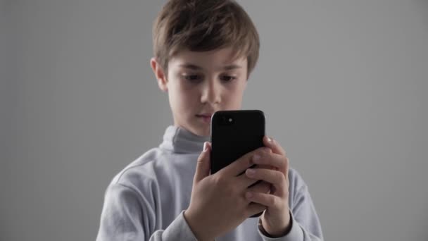 若者の肖像 11-12 年歳の少年は、白い背景の上にスマート フォンを使用して — ストック動画