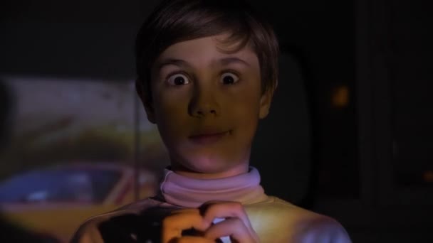 Lite rädd pojke tittar på skräckfilm eller Video på Tv eller dator i det mörka rummen. Reflektion på hans ansikte. — Stockvideo