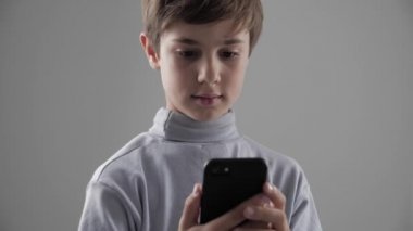 Genç çocuk beyaz arka plan üzerinde Smartphone kullanarak çocuk portresi. Erkek plaing oyunları Smartphone cep telefonu ile.