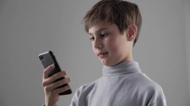 Genç çocuk beyaz arka plan üzerinde Smartphone kullanarak çocuk portresi. Erkek plaing oyunları Smartphone cep telefonu ile.