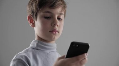 Genç çocuk beyaz arka plan üzerinde Smartphone kullanarak çocuk portresi. Erkek plaing oyunları Smartphone cep telefonu ile.