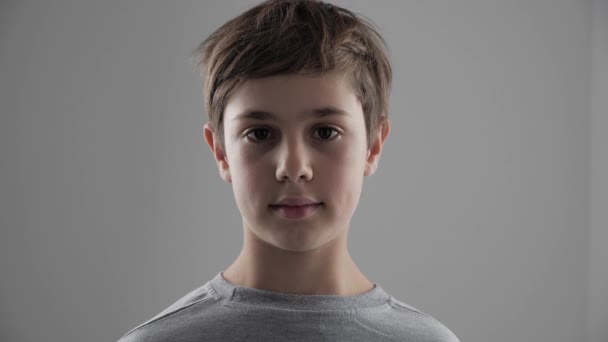 Portrait des süßen 11 - 12 jährigen Jungen, der auf weißem Hintergrund in die Kamera schaut — Stockvideo