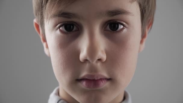 Close up Retrato de bonito jovem 11 - 12 anos de idade menino olhando para a câmera no fundo branco — Vídeo de Stock