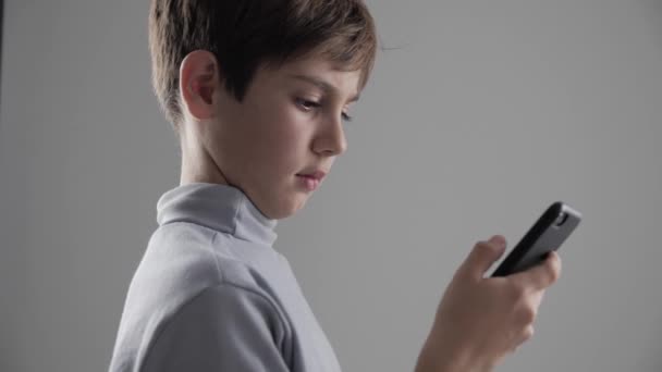 Porträtt av ung 11-12 år gammal pojke med Smartphone på vit bakgrund — Stockvideo