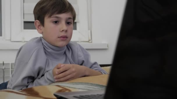 Дитячий хлопчик дивиться відео на ноутбук вдома на ліжку . — стокове відео