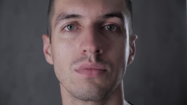 Retrato de close-up de jovem homem elegante em fundo cinza — Vídeo de Stock