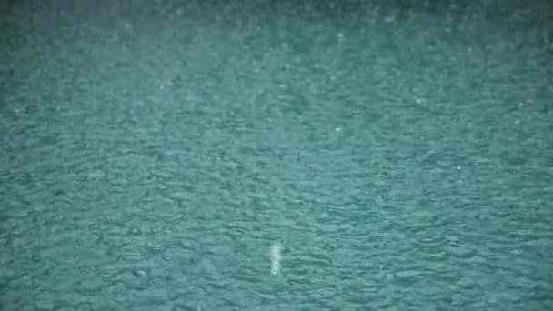 Сильний дощ на водяній стрільбі. Краплі дощу потрапляють у воду при повільному русі . — стокове відео