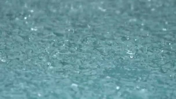 Zware regenval op het water fotograferen. Regendruppels vallen in het water in slow motion. — Stockvideo