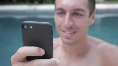 Genç adam Smartphone Göleti'nde yaz tatile kullanarak.