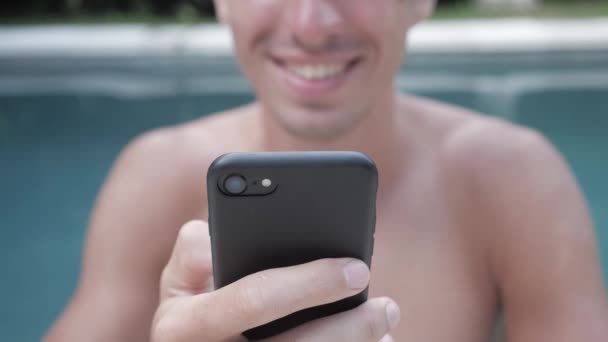 Ung mand bruger smartphone ved poolen på sommerferie – Stock-video