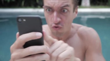 Kızgın adam agresif smartphone açık yüzme havuzunda tatile kullanır.