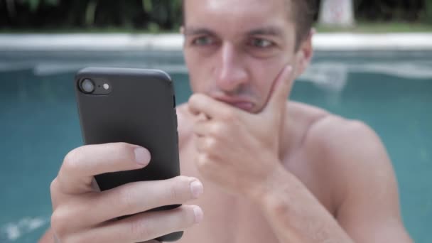 Boze man agressief gebruikt smartphone buiten in het zwembad op vakantie. — Stockvideo