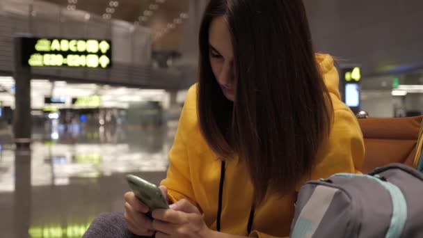 Jeune femme utilisant un smartphone dans la salle d'attente à l'aéroport — Video