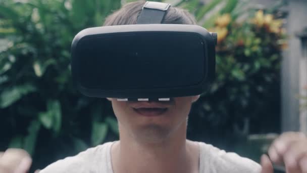 Крупный план портрет молодого человека использует очки виртуальной реальности на открытом воздухе в саду — стоковое видео