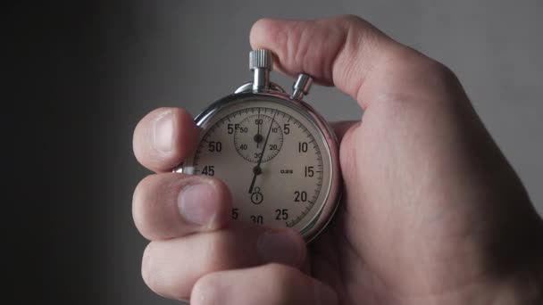 Primer plano de una persona que pone en marcha un cronómetro con fondo gris. 4K, 10 BIT, 4: 2: 2 . — Vídeos de Stock