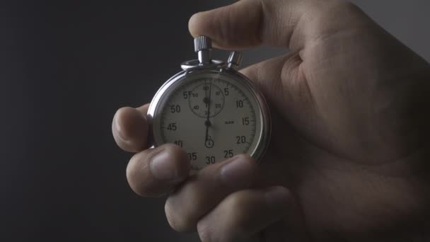 Primer plano Mans Hand poner en marcha un cronómetro en fondo gris 4K, 10 BIT, 4: 2: 2 — Vídeo de stock