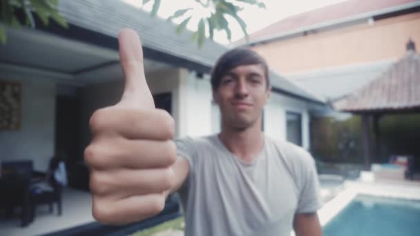 Joven feliz dando un pulgar hacia arriba y sonriendo al aire libre en el patio — Vídeos de Stock