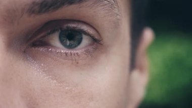 Genç adam yeşil göz, yeşil doğa arka plan açık Close-up
