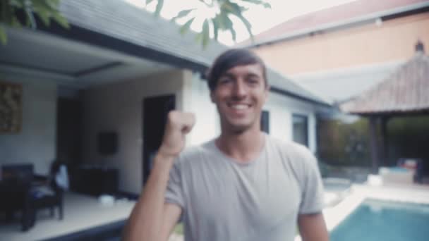 Felice giovane uomo dando un pollice in su e sorridente all'aperto nel cortile — Video Stock