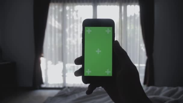 Nahaufnahme junger Mann auf dem Bett liegend mit Smartphone Green Screen Chroma-Key Greenscreen Sharing authentischen sozialen Medien — Stockvideo