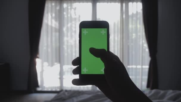 Close up Giovane uomo sdraiato sul letto con smartphone schermo verde chroma-key greenscreen condivisione di autentici social media — Video Stock
