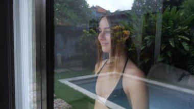 Kadın pencereden dışarı bakar ve elini sallayarak birine elveda diyor. 4k, ağır çekim.