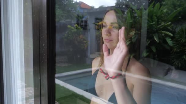 Femme regarde par la fenêtre et dit au revoir à quelqu'un, agitant la main. 4k, au ralenti . — Video