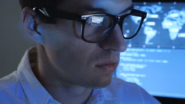 Close up Retrato de programador profesional de TI en gafas está trabajando en la computadora en el centro de seguridad cibernética lleno de pantallas . — Vídeos de Stock