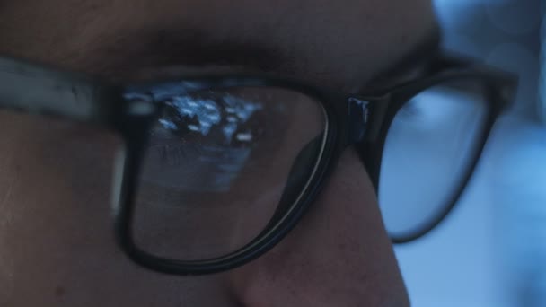 データ センターで働く男性のハッカーのクローズ アップ目のオフィスで残業のメガネの若い男オタク プログラマーのクローズ アップ — ストック動画