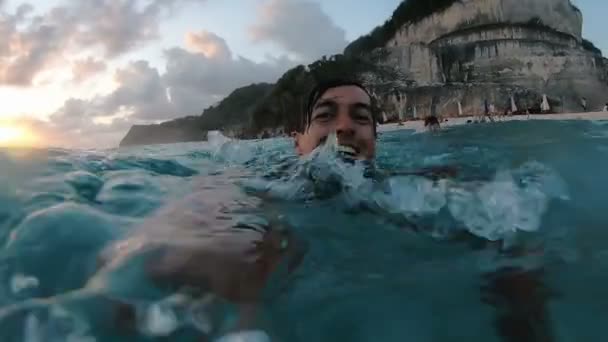 Jonge man zwemt in de Oceaan en duiken onder water nemen van een selfie met zichzelf op de camera op een tropisch strand. — Stockvideo