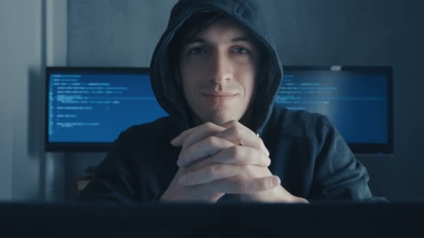 Portret van de Man in de kap zit aan tafel en codering op de laptop. Hacker in hoody werken bij computer in datacenter gevuld monitor pagina 's — Stockvideo