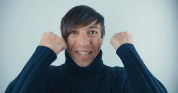 Retrato de Joven Sorprendido en Suéter Negro sobre fondo blanco. Victoria o éxito repentino. Concepto de victoria . — Vídeo de stock