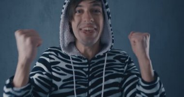 Portrait of Happy Young Man in kigurumi zebras on gray background. Emotions of joy and delight