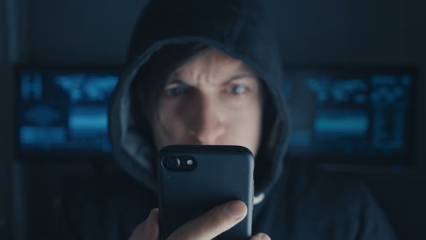 Hacker enojado en el capó utilizando el teléfono inteligente. Cibercriminales gritan y muestran agresividad — Vídeos de Stock