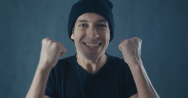 Portrait of Amazed Surprised Young Man in Black Shirt. Sudden Victory or Success. Victory concept. Thumb up