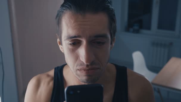 Strzał płacz człowieka czytanie wiadomości na smartfonie, ze łzami w domu — Wideo stockowe