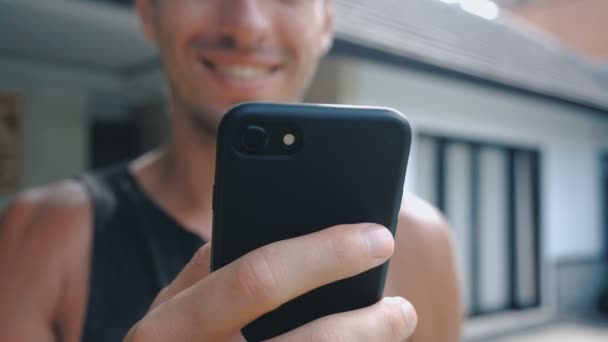 Close up of Smiling Young Man Using Smartphone, Browsing in Internet or Checking Social Networks at courtyard or garden background — Stock Video