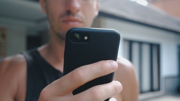 Close-up de homem usando smartphone ao ar livre. Jovem com computador tablet. Um homem no quintal perto de casa em redes sociais usando um smartphone . — Vídeo de Stock