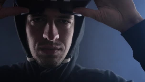 Закрыть Молодой человек в капюшоне с помощью гарнитуры виртуальной реальности на черном дымчатом фоне . — стоковое видео