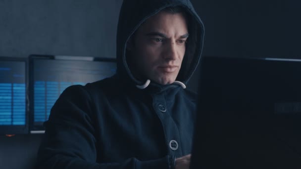 サイバー犯罪の概念。暗いオフィスの部屋のコンピューターに取り組んでいるフードの男ハッカーをしたかった — ストック動画